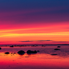 Veripunane päikeseloojang rannas panoraamina